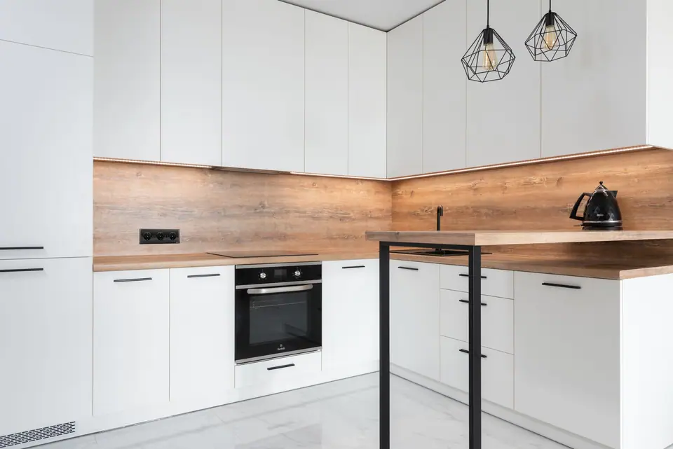 Cozinha contemporânea com armários brancos, bancada de madeira e pendentes geométricos