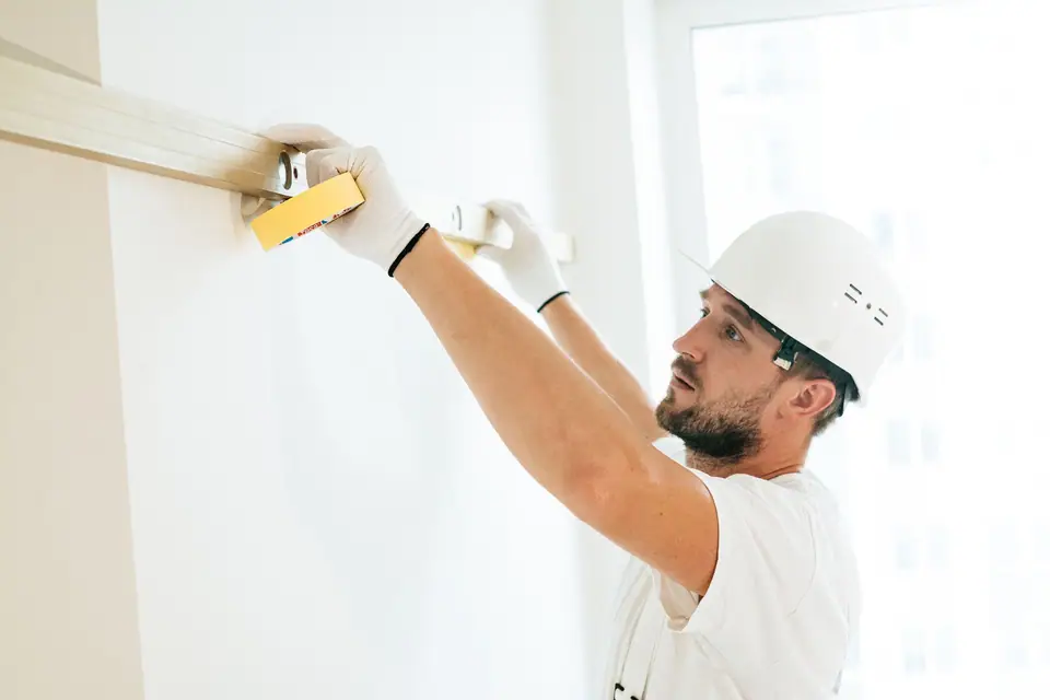 Profissional de capacete conferindo uma parede com nível de bolha